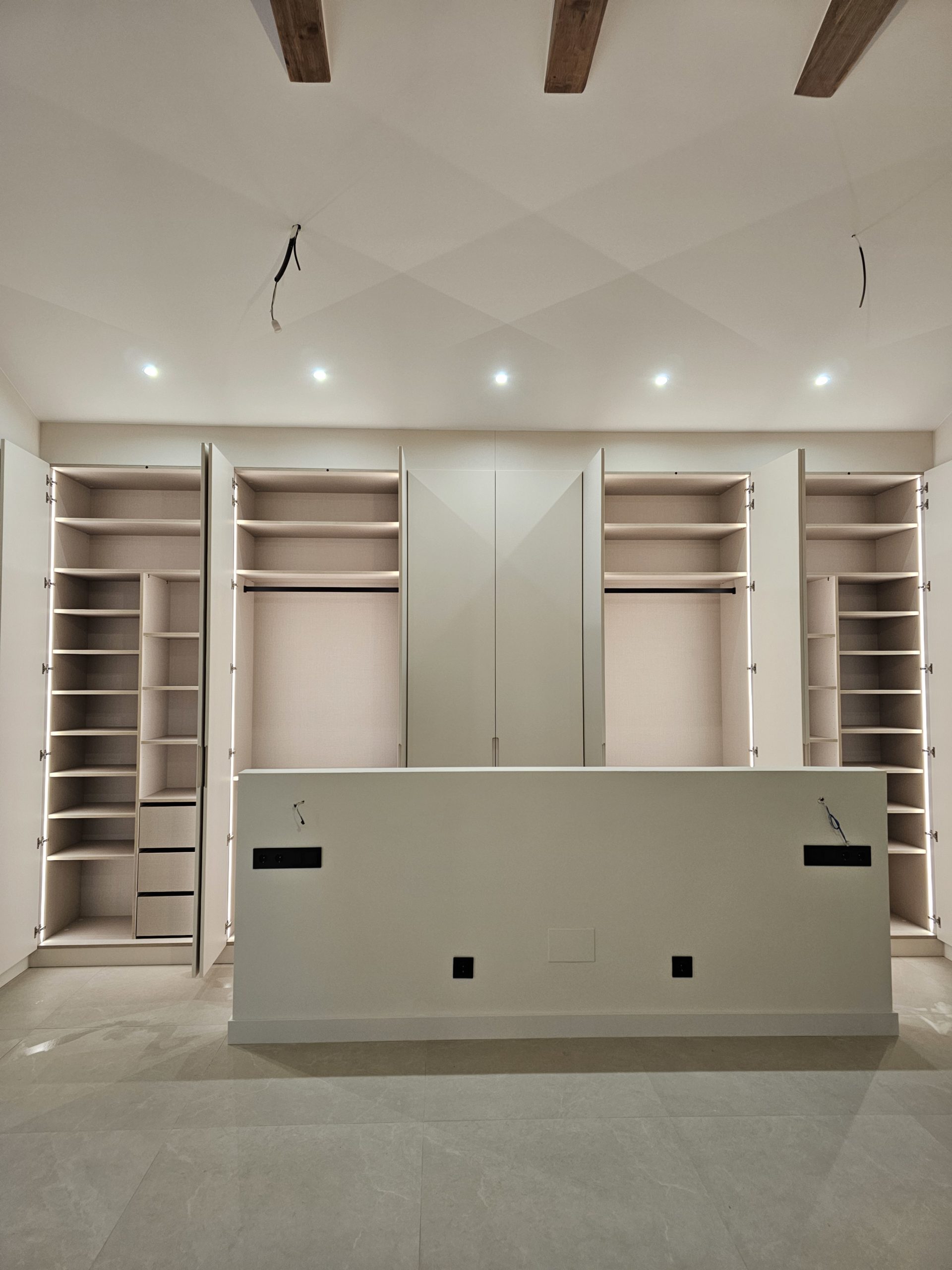 Vestidor a medida con puertas lacadas crema y uñero integrado, interior en melamina tono sal y luz LED en Martorell